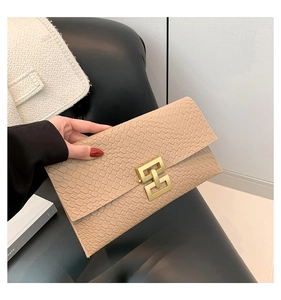 Detail of beige envelope clutch bag featuring faux crocodile texture and gold geometric buckle