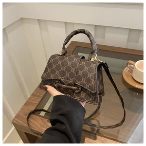 Dettaglio della borsa a tracolla marrone vintage con motivo classico e finiture dorate