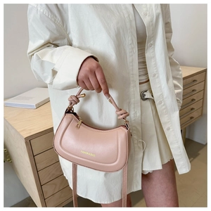 Close-up of pink semi-circular handbag with knotted handle and fashion text detail