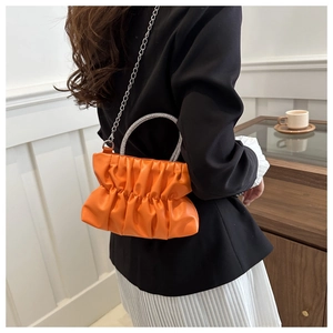 Detail van oranje geplooide emmertas met handvat van strass en zilveren ketting
