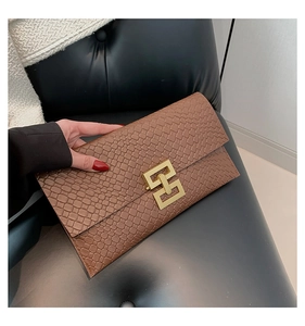 Detail of brown faux snake texture envelope clutch bag with gold geometric buckle