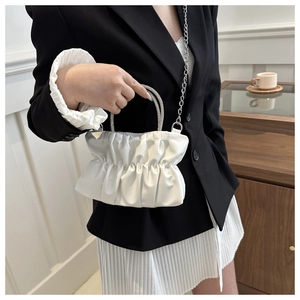 Detail of white pleated cloud bag featuring rhinestone handles and silver chain strap