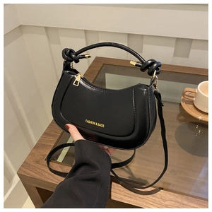 Close-up of black leather handbag with a knotted top handle and gold metal details
