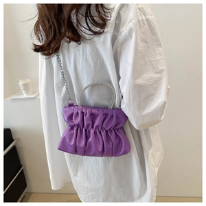 Sac bandoulière plissé violet avec poignée en strass étincelants sur chemise blanche