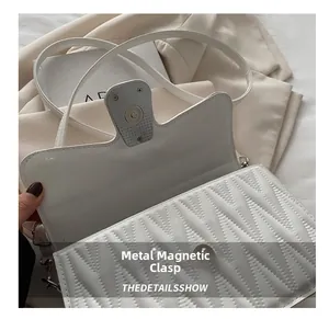 Détail de la boucle magnétique argentée sur un sac à bandoulière carré blanc matelassé