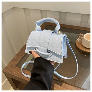 Dettaglio di una borsa a mano in pelle azzurra con trama litchi in un ambiente lifestyle