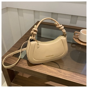Detail of beige crescent hobo bag with knotted handle and fashion gold lettering