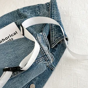 Detail of white nylon shoulder strap with black buckle on blue denim jacket