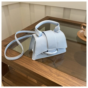 Dettaglio mini borsa a trapezio celeste in pelle martellata con manico curvo