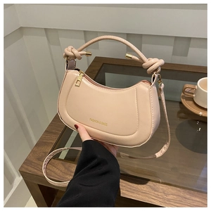 Detail of beige half-moon bag featuring unique handle knots and golden zipper hardware