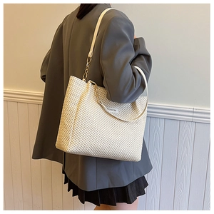 Close-up of woven tote bag with leather gold chain strap and Fashion label tag