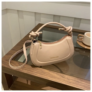 Detail of beige crossbody bag with knotted handle and fashion print on leather texture