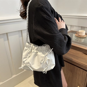 Sac seau plissé blanc avec nœuds et chaîne en argent dans une scène de style de vie