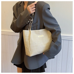 Detail of beige woven tote bag showing lattice texture and gold chain shoulder strap