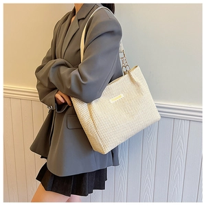 Beige woven straw tote bag with leather shoulder straps and golden chain accents