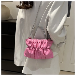 Macro detail of pink pleated cloud bag with sparkling rhinestone handle and silver chain strap
