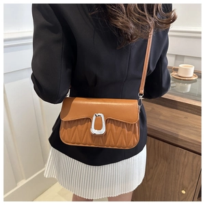 Détail de sac à bandoulière marron matelassé avec boucle argentée et coutures en vagues