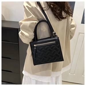 Close-up of quilted black leather handbag with gold metal zippers and textured stitching