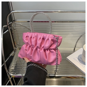 Détail du sac à main plissé rose montrant la poignée en strass argentés et la chaîne