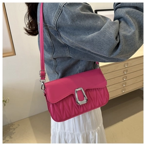 Détail d'un sac bandoulière rose fuchsia avec texture matelassée et boucle en métal argenté