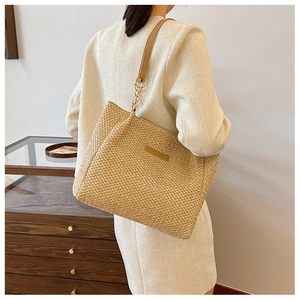 Close-up of woven straw tote bag texture with FASHION leather patch and chain strap