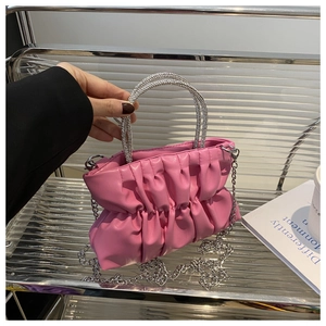 Détail du sac à main plissé rose avec poignées en strass brillants et fine chaîne argentée