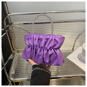 Détail d'un sac à main plissé violet avec poignée en strass et bandoulière chaîne argentée