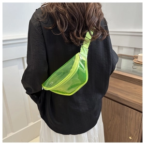 Rear view of a neon green transparent PVC belt bag worn crossbody style on a black top