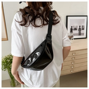 Glossy black leather chest bag worn cross-body style with adjustable nylon strap