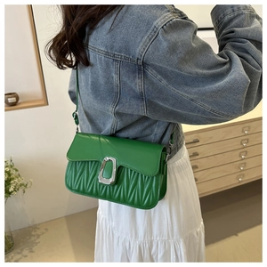 Détail du sac bandoulière vert montrant la texture matelassée et la boucle en métal argenté