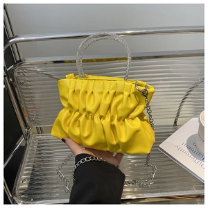 Détail du sac plissé jaune avec poignées en strass et bandoulière chaîne argentée