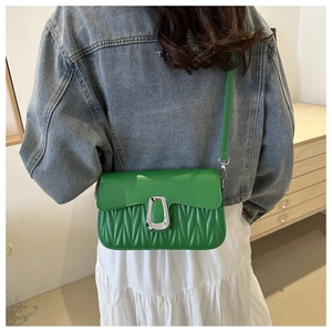 Gros plan d'un sac à bandoulière vert vif avec design plissé et boucle argentée en U
