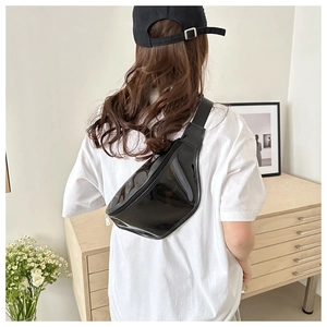 Glossy black patent leather belt bag with adjustable strap worn in a lifestyle setting