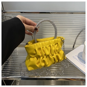 Détail d'un sac nuage plissé jaune vif avec poignée ronde en strass étincelants et chaîne