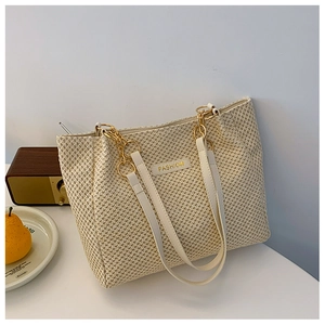 Detail of cream woven tote bag with FASHION gold plaque and elegant chain straps