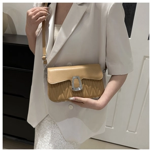 Sac bandoulière marron clair avec matelassage en V et boucle métallique porté par modèle