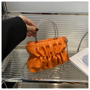 Détail du sac à main plissé orange avec poignées anneaux en strass et chaîne argentée