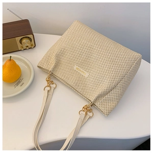 Detail of cream woven tote bag showing houndstooth texture and leather chain strap