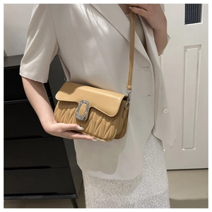 Détail du sac à bandoulière matelassé beige avec boucle en U porté par un mannequin