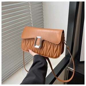 Détails des plis accordéon marron et fermoir argenté en U sur le sac à bandoulière