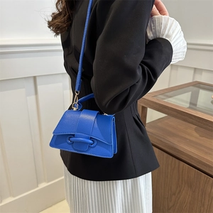 Borsa a tracolla blu reale con trama litchi e chiusura cilindrica sulla modella
