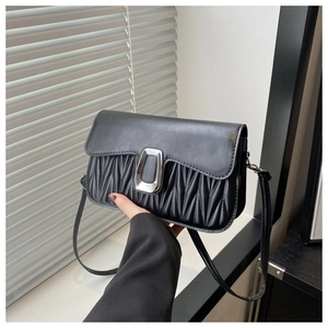 Détail du sac à bandoulière en similicuir noir avec design plissé et boucle argentée en U