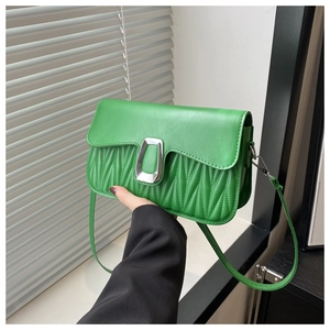 Détails d'un sac bandoulière vert avec plis verticaux et fermoir métallique argenté en U
