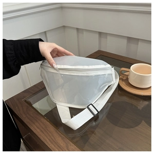 Detail of transparent PVC chest bag with white trim and adjustable strap on a wooden table