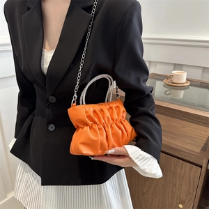 Sac plissé orange vif avec poignées en strass et chaîne argentée porté par le mannequin