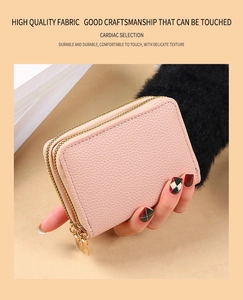 Close-up of hand-held pink lychee texture leather wallet with double gold zippers