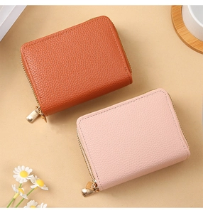 Flat lay of pink and tan pebble leather mini wallets with golden heart-shaped zippers
