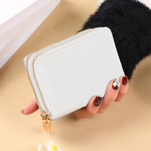 Close-up of light blue pebbled leather card holder with double golden zippers held in hand