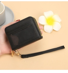 Détail du porte-cartes en cuir grainé noir avec fenêtre d'identité et zip doré brillant