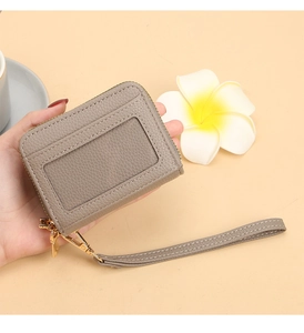Détail d'un porte-cartes en cuir gris avec fenêtre transparente et zip doré brillant